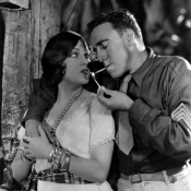 1928: Silent screen star Gloria Swanson (1897 - 1983) shares a match with a US marine in a scene from the film 'Sadie Thompson'. It was directed by Raoul Walsh for Gloria Swanson Pictures Corporation and United Artists.